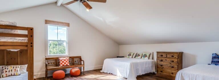 Second-floor bonus bedroom with sloped ceilings and ceiling fan prone to uneven cooling and hot spots.