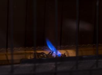 a small blue flame inside of a dark furnace