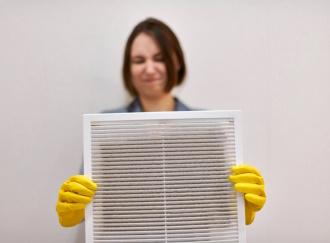 Woman holding dirty and dusty ventilation grille, disgusted
