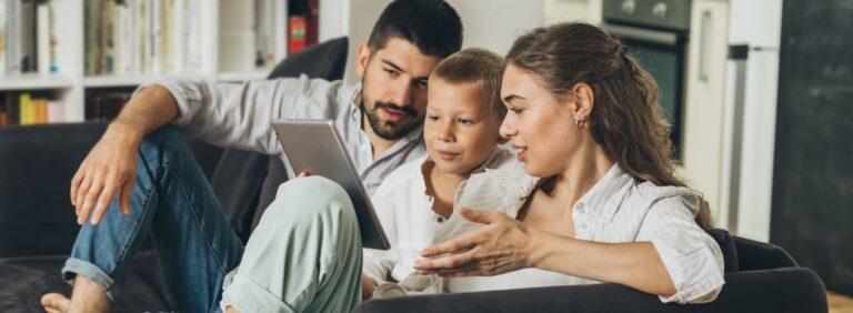 Young family reviewing home warranty information on a tablet while sitting together in their living room