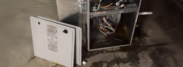 Open water heater showing internal components and signs of leakage on the floor