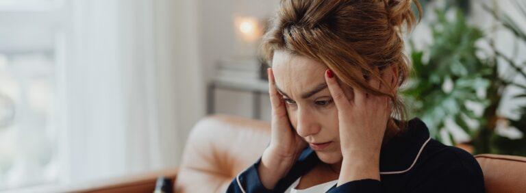 Concerned woman smelling burning odor in her home, sitting near a window