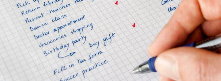 Handwriting a to-do list on graph paper with tasks like doctor appointment and grocery shopping