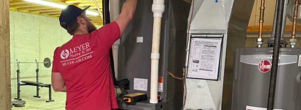 Meyer Heating & Air technician performing routine boiler maintenance inside a residential utility room in St. Louis