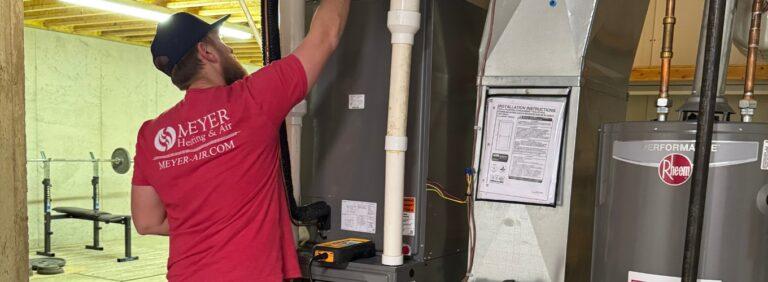 Meyer Heating & Air technician performing routine boiler maintenance inside a residential utility room in St. Louis