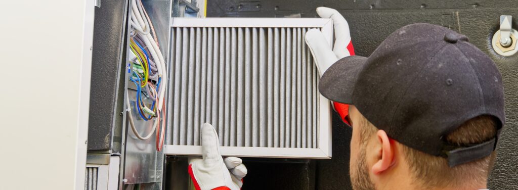 Technician replacing an HVAC air filter during a maintenance visit, representing Meyer Heating & Air’s professional HVAC maintenance services.