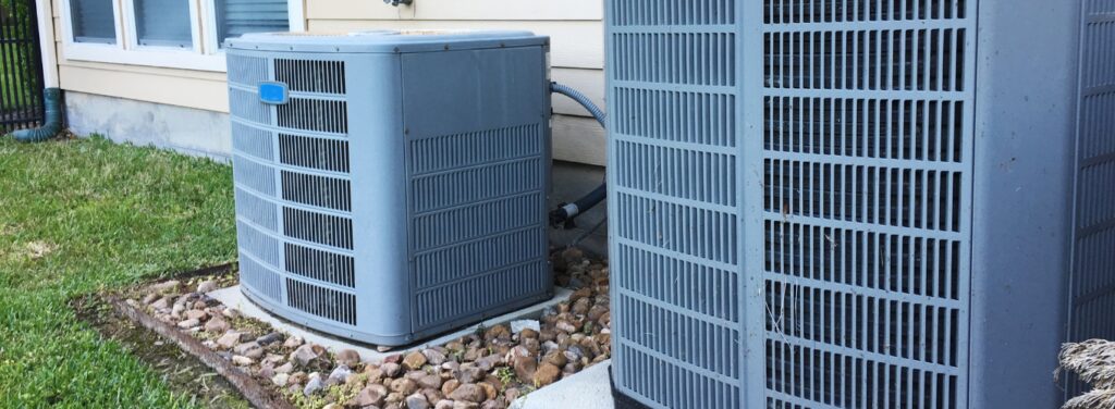 Two outdoor HVAC heat pump units beside a home, representing the different types of heat pumps used in residential heating and cooling systems.