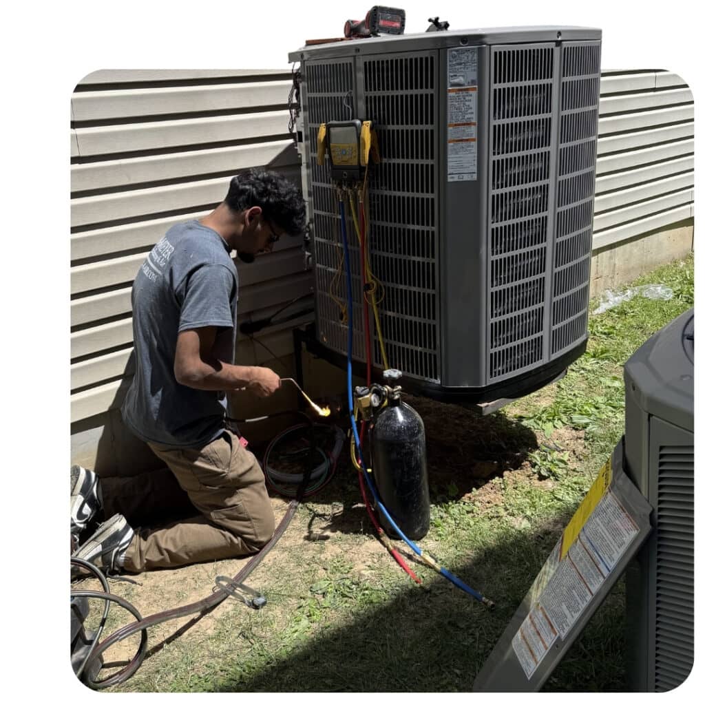HVAC technician brazing refrigerant lines with a torch during an outdoor air conditioner installation.