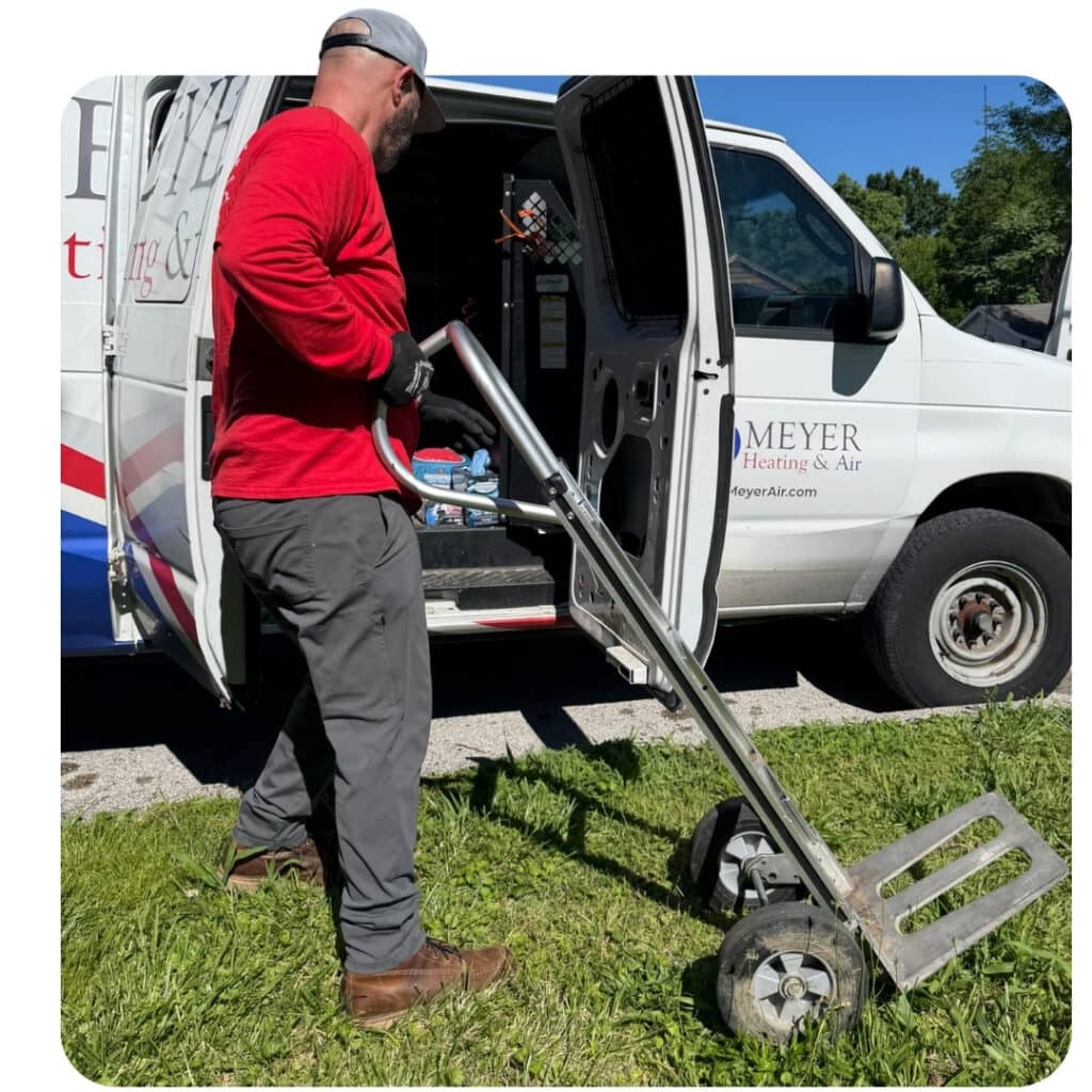 Meyer Heating & Air technician unloading a heavy-duty appliance dolly from a service van for an HVAC installation.