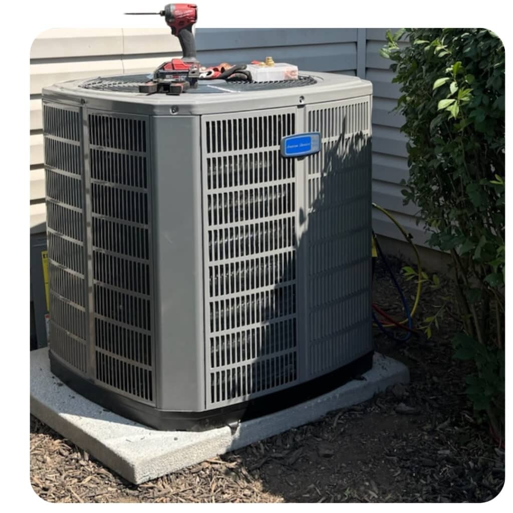 American Standard outdoor air conditioning and heat pump condenser installed on an equipment pad during maintenance.