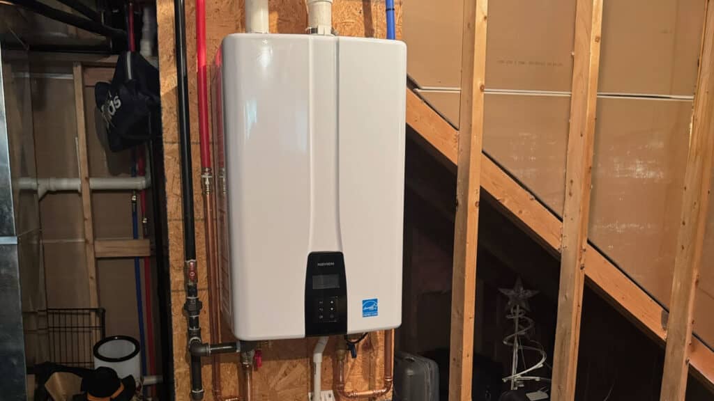 Energy Star-certified tankless water heater installed on wood wall studs in a residential utility room.