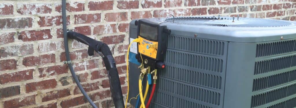 Digital diagnostic manifold gauge hooked up to an outdoor air conditioning condenser unit during a capacitor and refrigerant diagnostic.